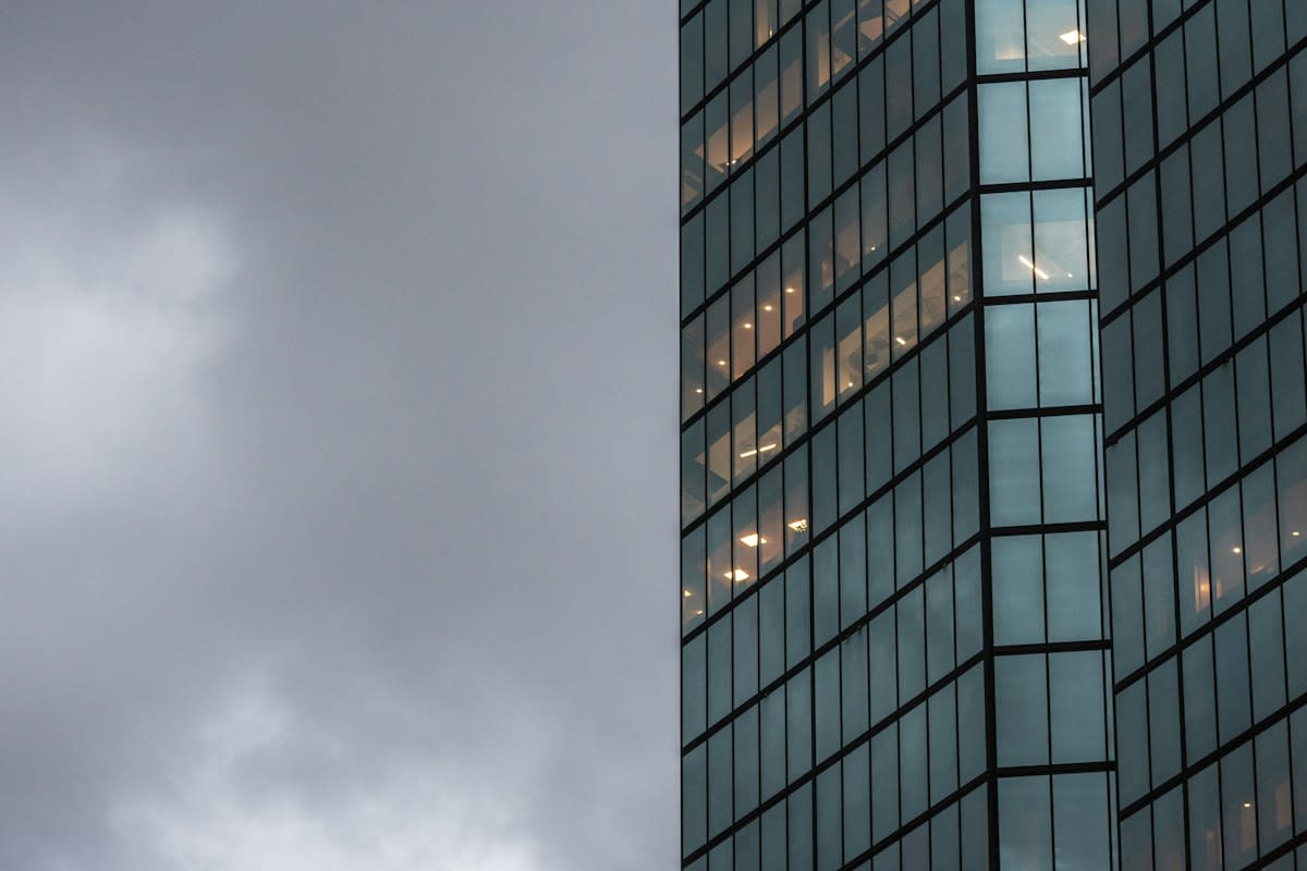 Modern glass skyscraper reflecting a grey sky