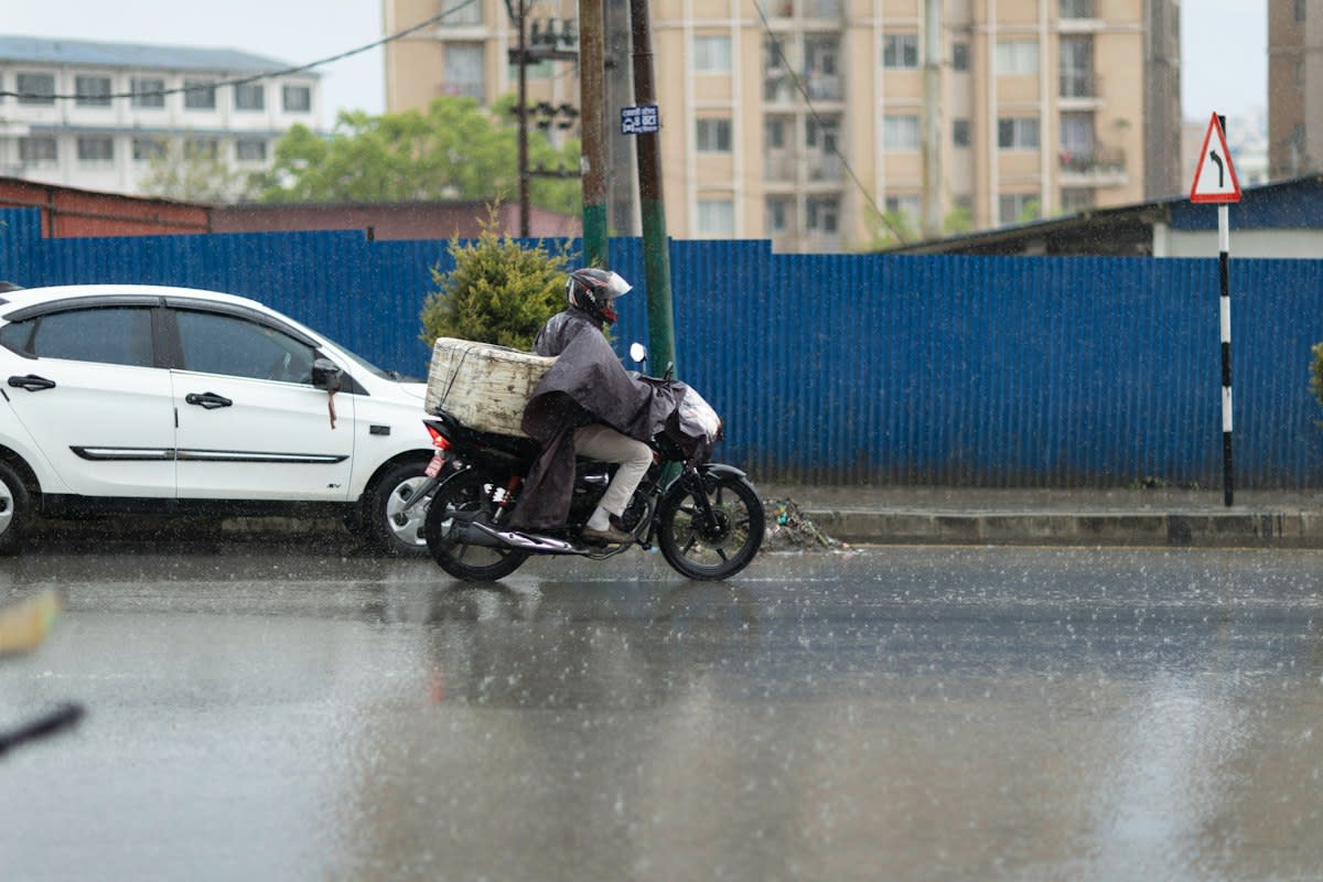 Courier looking at smartphone in city rain