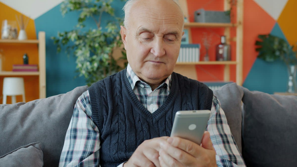 Elderly person using a smartphone in a modest living room