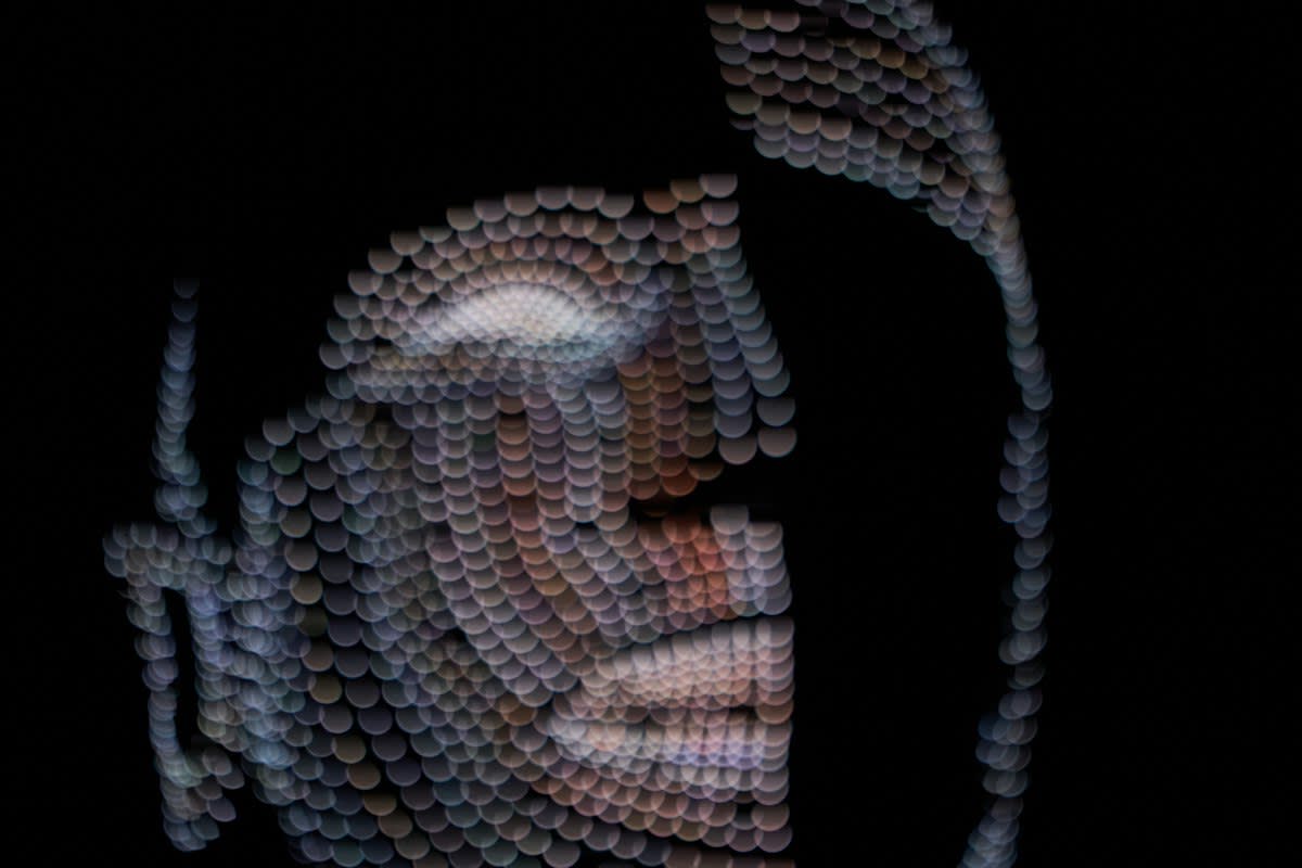 Abstract digital representation of a human face breaking into pixels