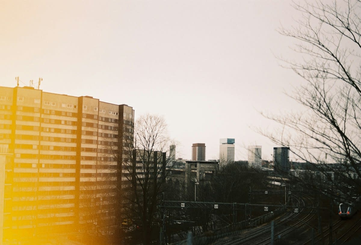 A silhouette of a person looking out a window into a gray city