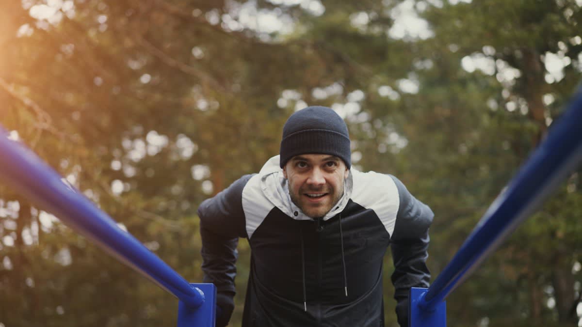 Man performing a planche on outdoor bars