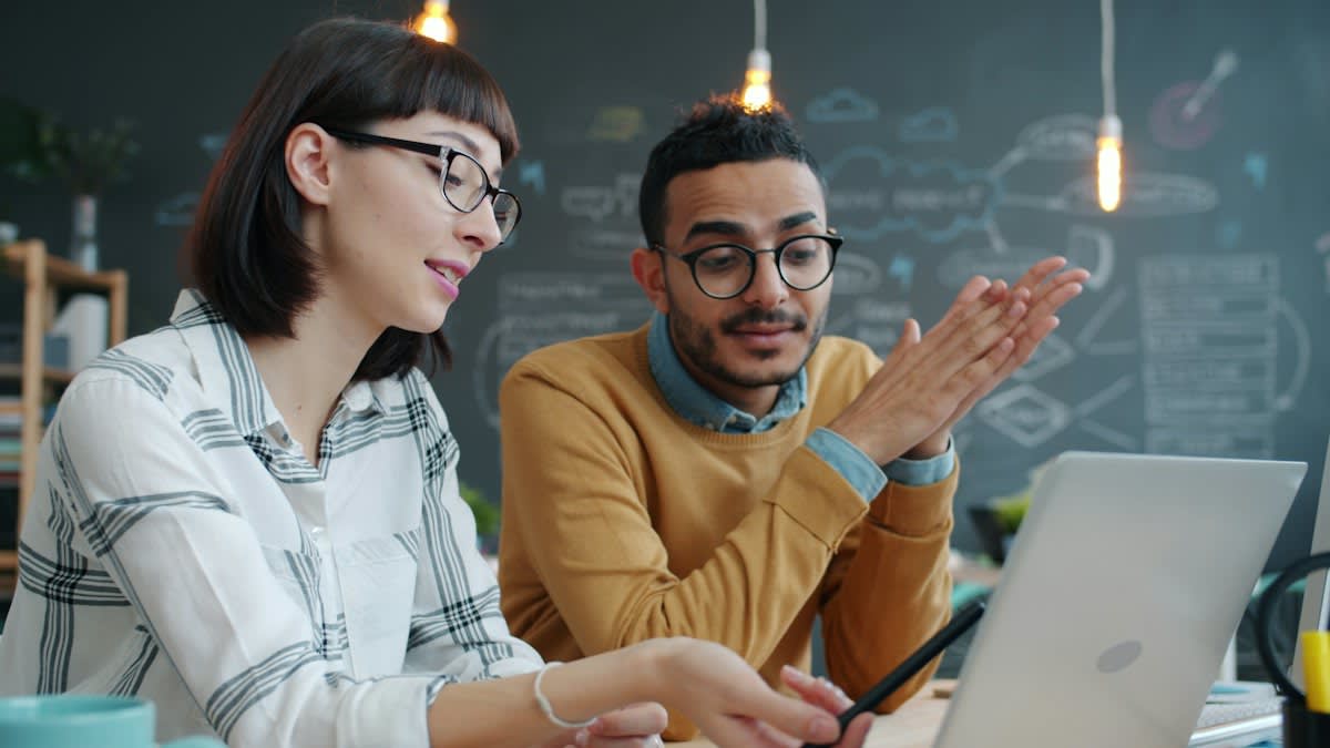 Two people arguing over a laptop in a modern office
