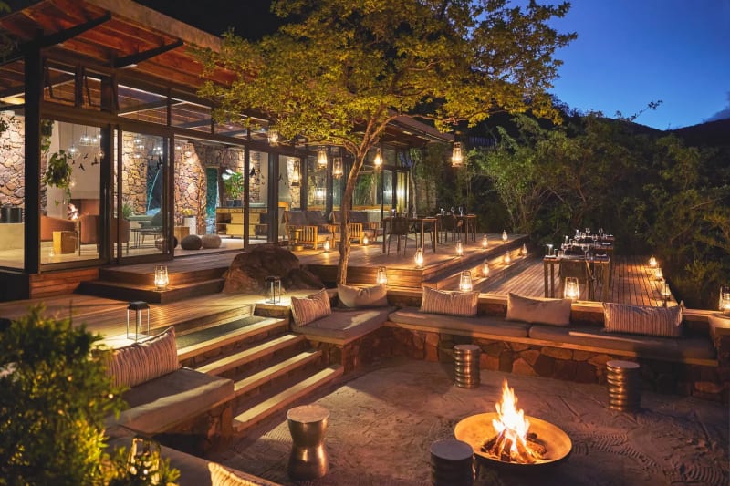 Cozy fire deck at Marataba Mountain with seating and lantern-lit ambiance under large trees in the evening