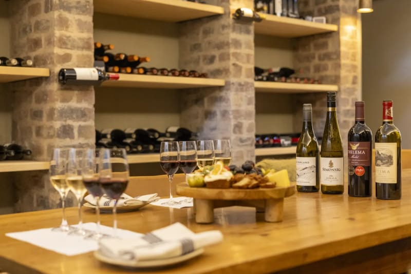 Wine tasting in the cellar at Monwana Lodge, with superb wines displayed in the background.