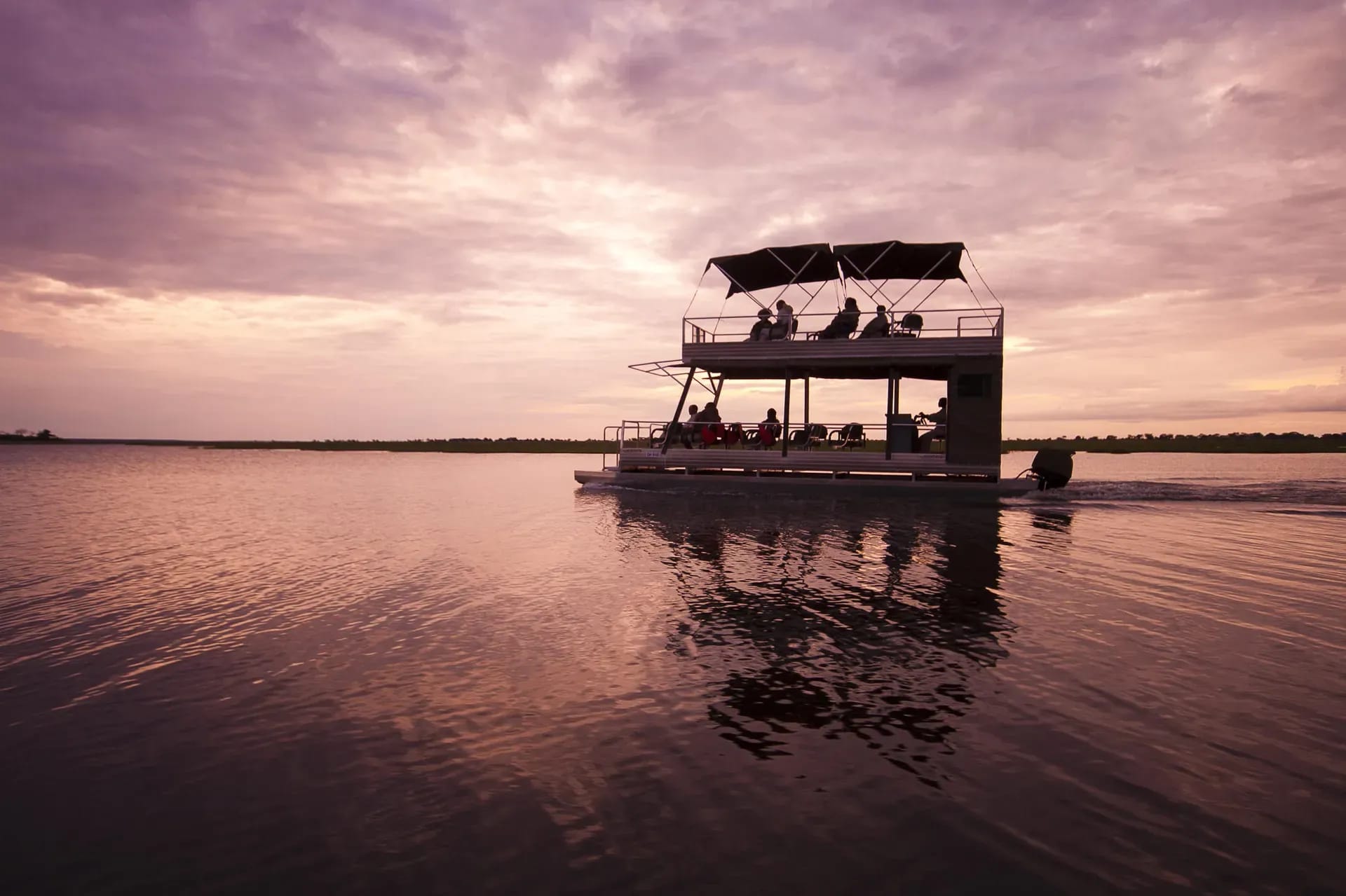 Family adventure boat trip on a lake with a shaded pontoon boat at sunset