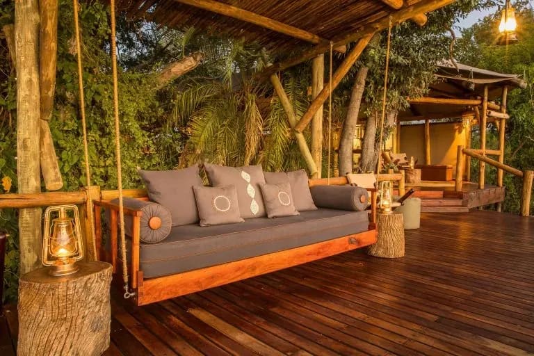 Kanana lodge outdoor lounge with cushioned sofas on a wooden deck under a thatched canopy