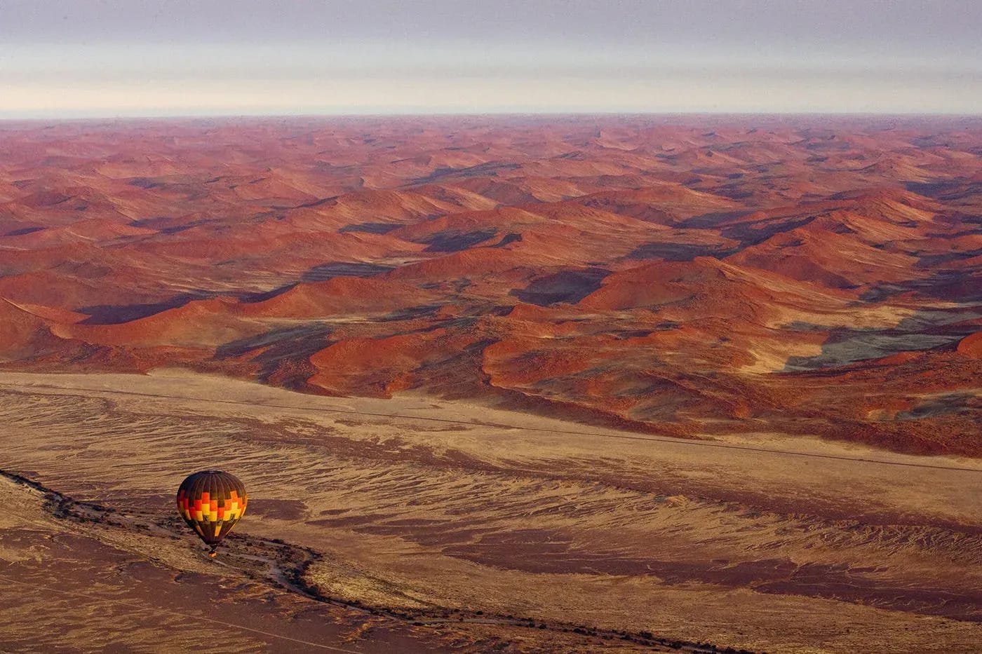 Expansive desert landscape with red rock formations and rugged canyons under a clear sky