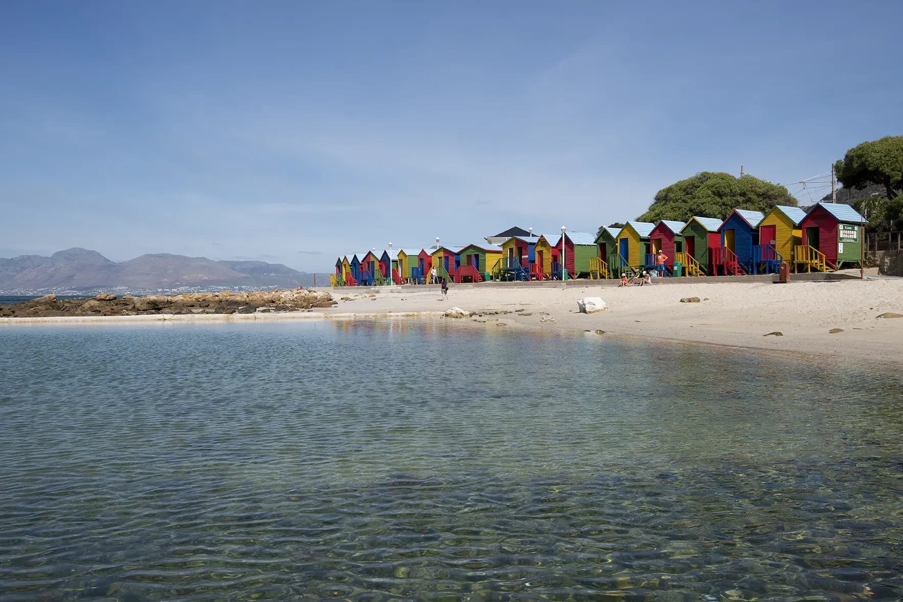 Row of colorful beach huts along St. James beach beside the ocean water