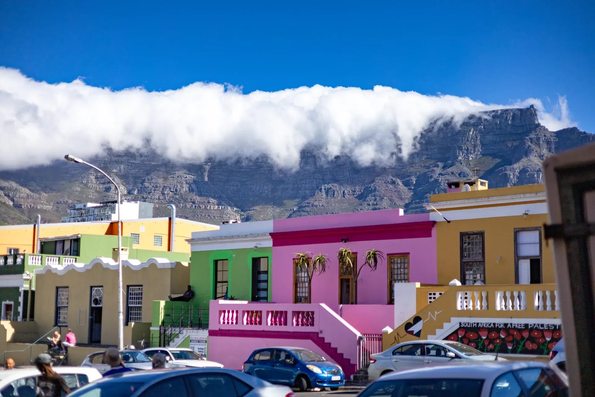 Brightly colored houses in a vibrant city neighborhood with mountains and blue sky in the background