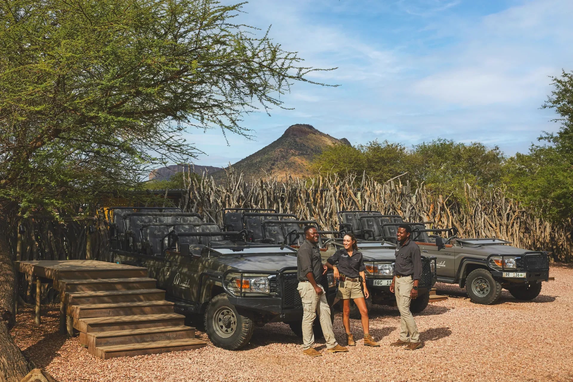 Safari field guides at Marataba standing next to an open safari vehicle under a tree with mountains in the background