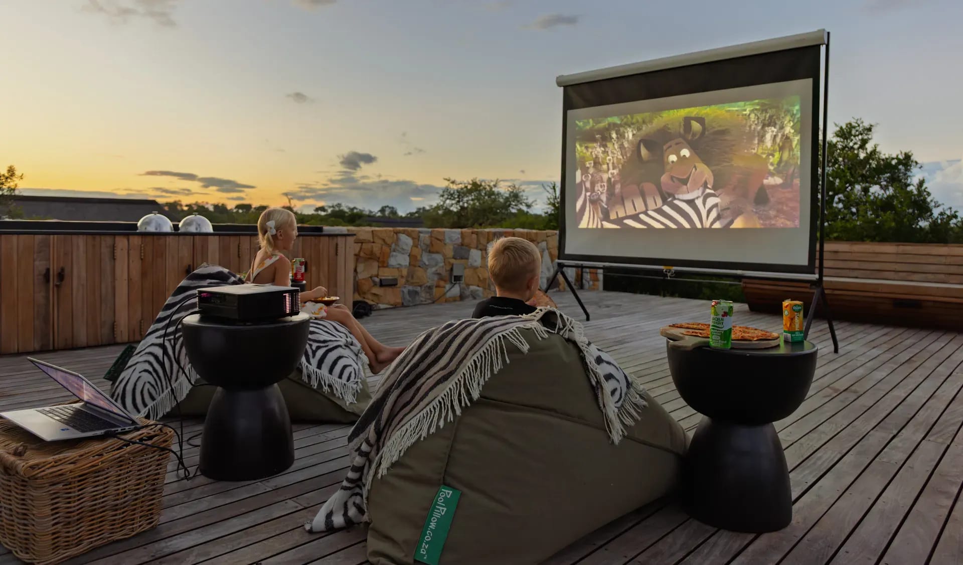 Child-friendly safari lodge with kids playing on a wooden playground structure overlooking a scenic landscape