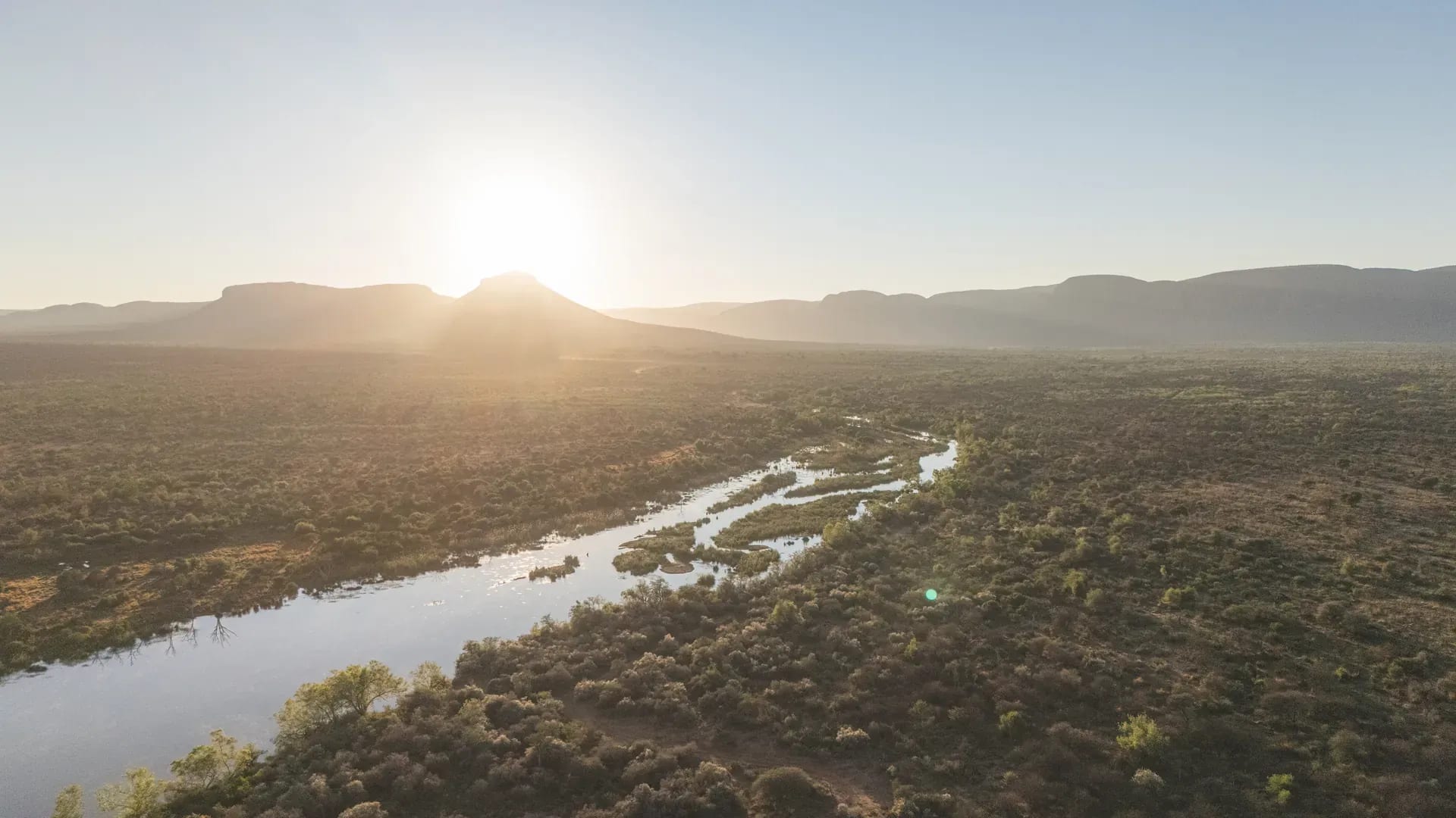 Aerial view of a rugged coastline with cliffs and the ocean at sunrise
