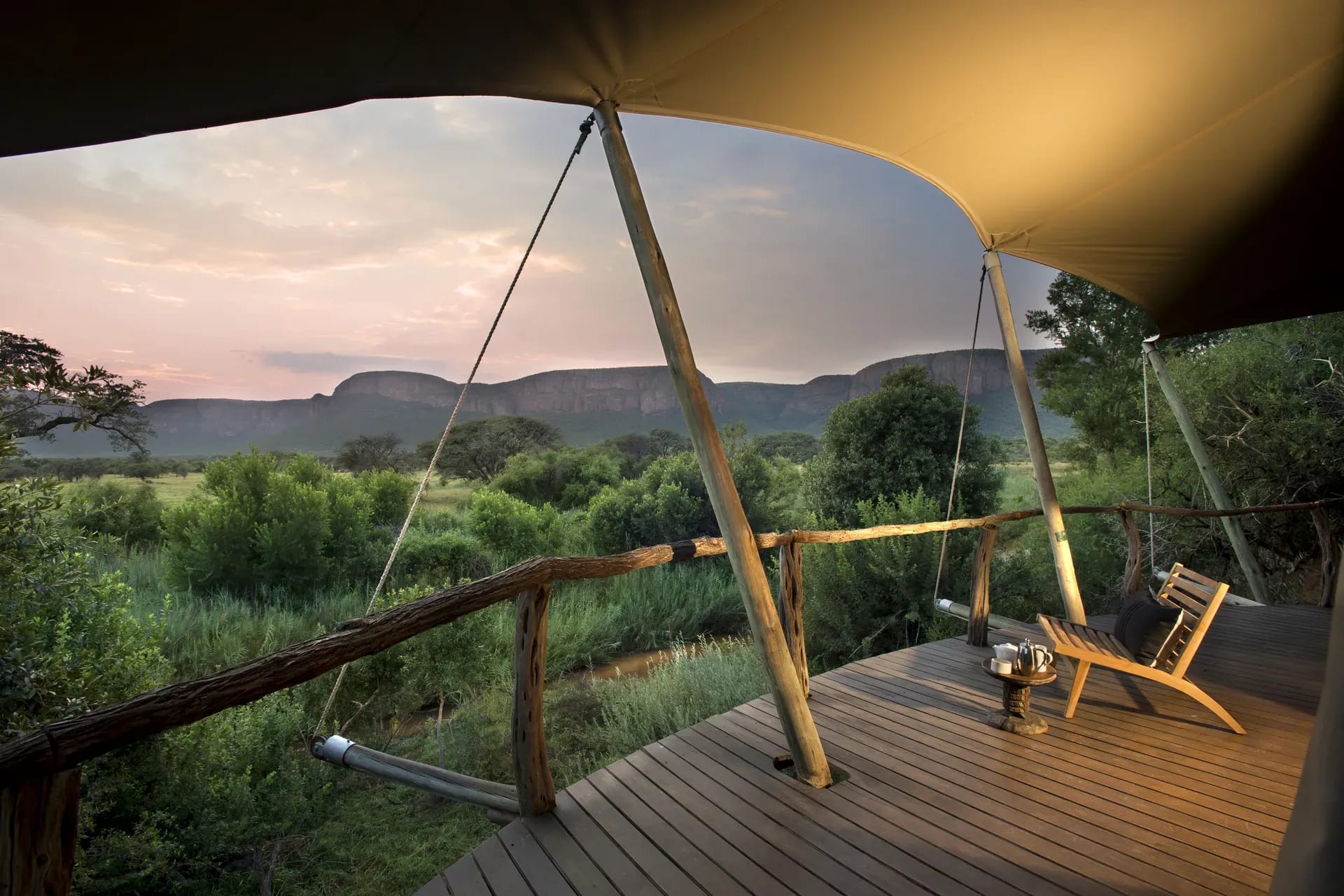 Private deck of a tented suite at Marataba Safari Lodge with sun umbrella, seating and scenic views of the bush and mountains