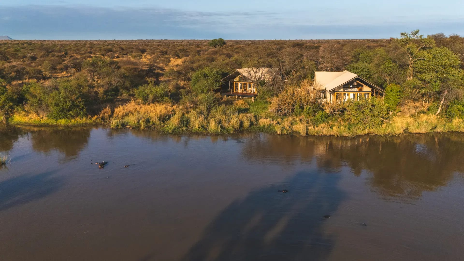 Marataba Residence Tent exterior with river view and hippos in the water.
