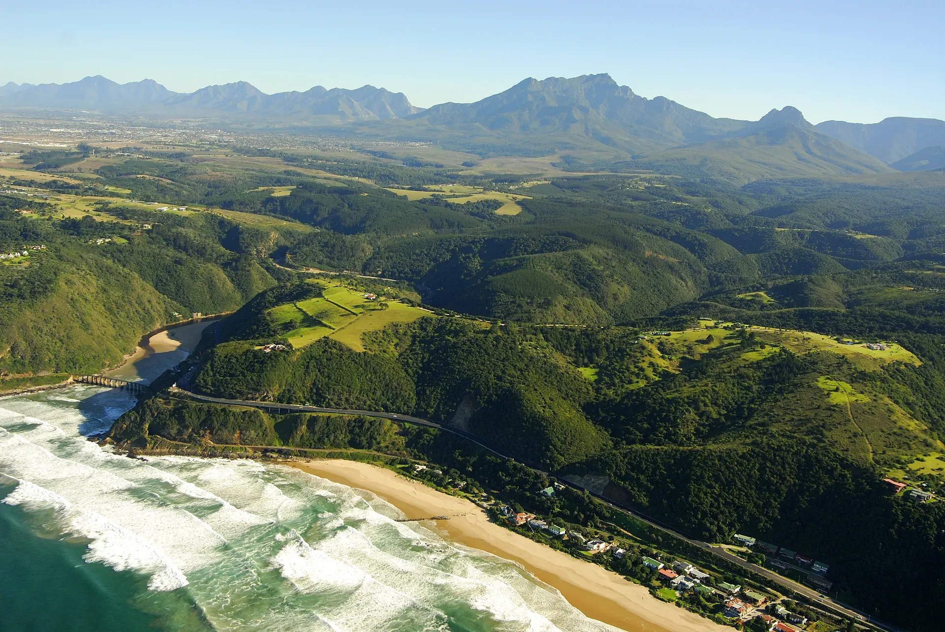 Scenic aerial view of South Africa's Garden Route with lush green hills, forested valleys, and distant mountains