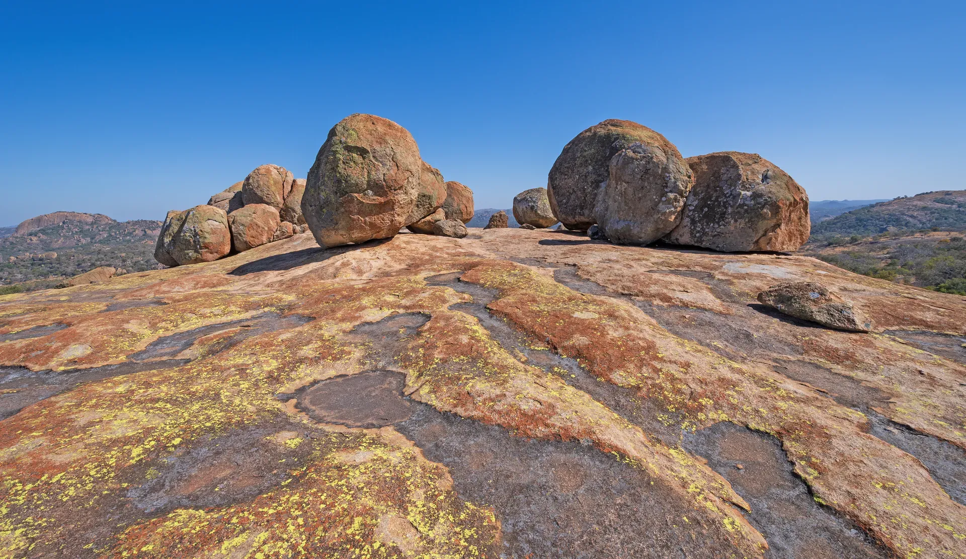 Distinctive granite rock formations in Matobo Hills rising above a golden grassy landscape under a clear blue sky