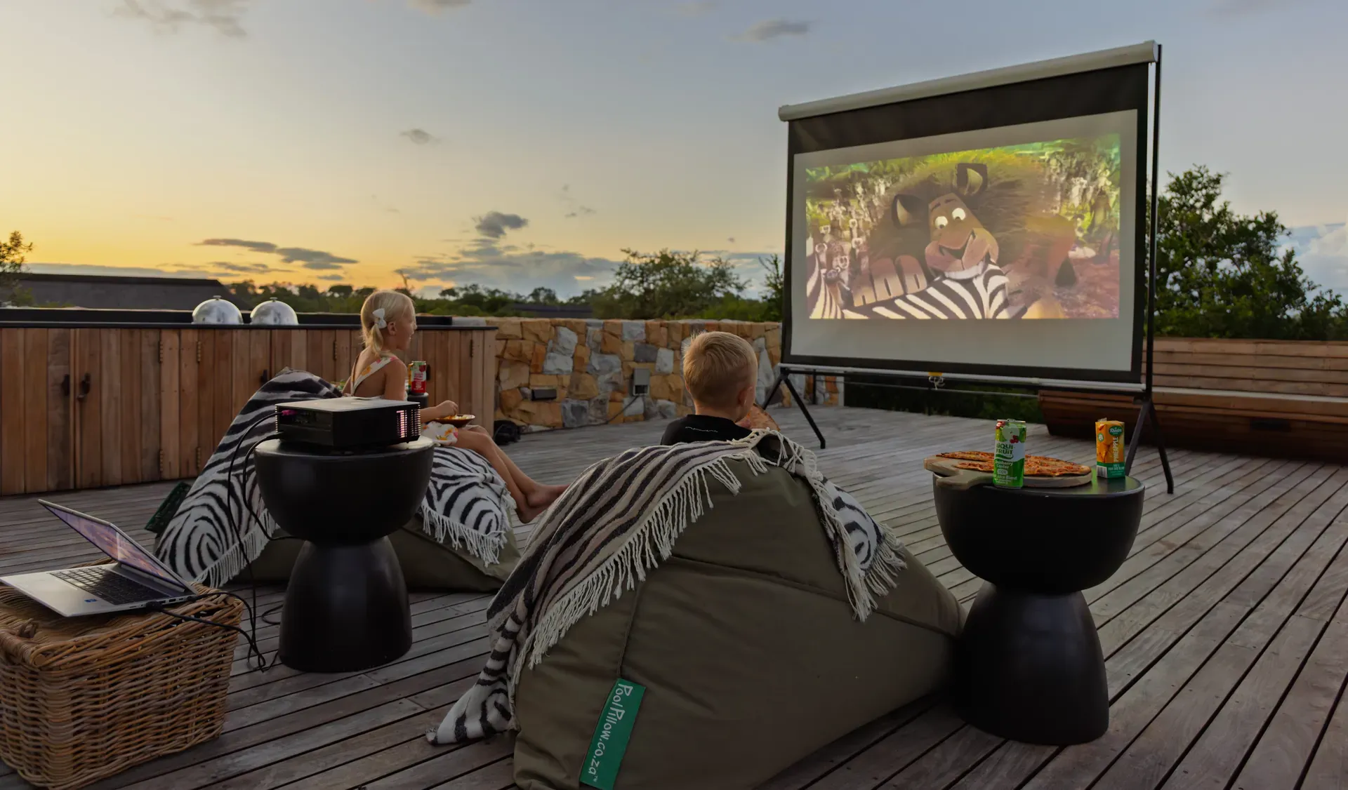 Child-friendly safari lodge with kids playing on a wooden playground structure overlooking a scenic landscape