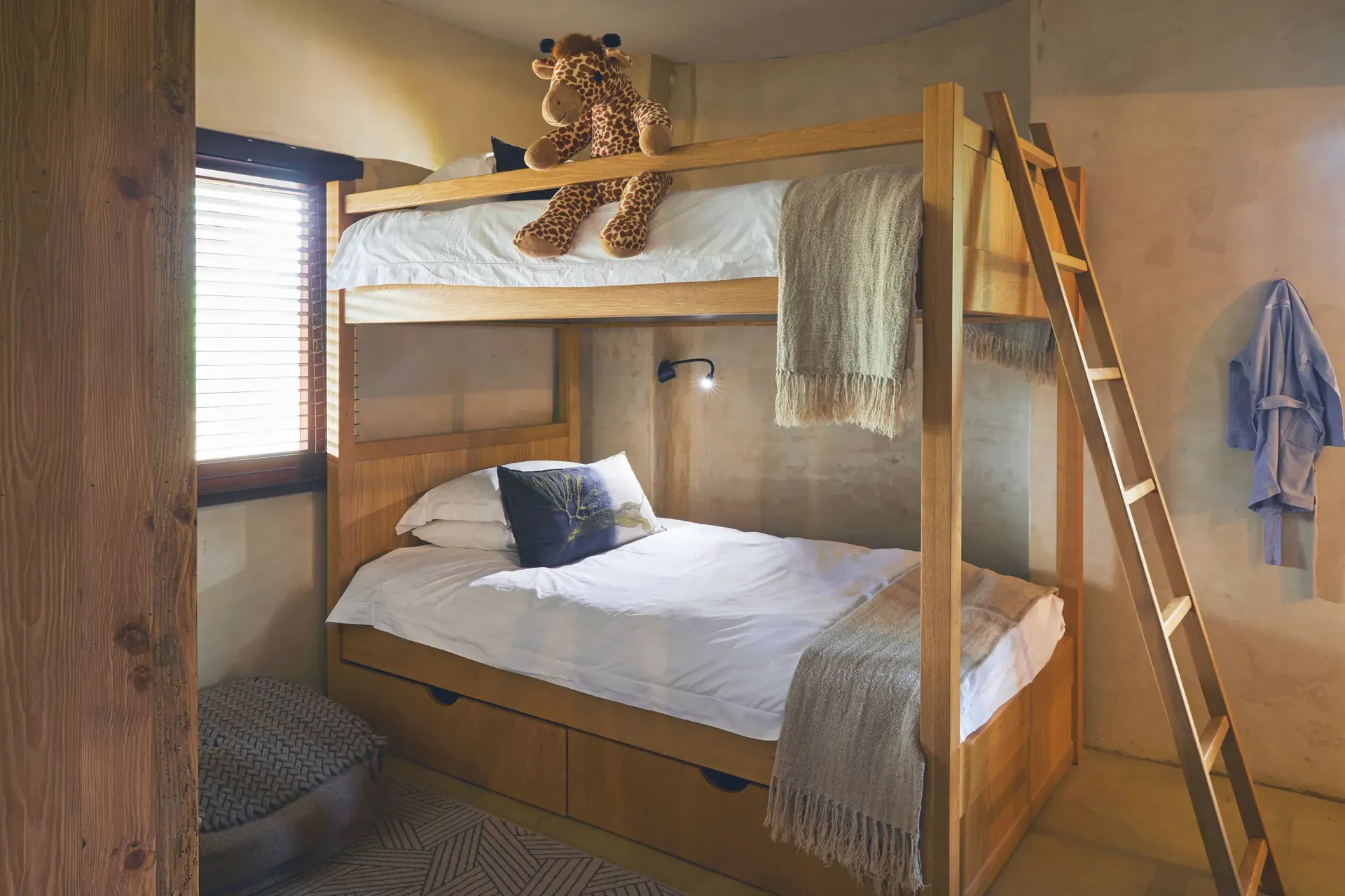 Family suite bedroom featuring a canopy bed with white linens, wooden posts, and cozy decor at a safari lodge