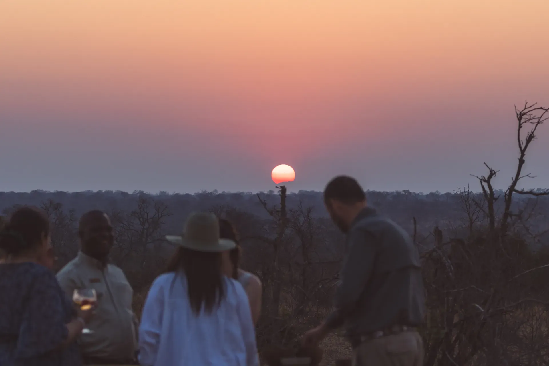 Guests enjoying group dining at sunset on a terrace overlooking a scenic landscape