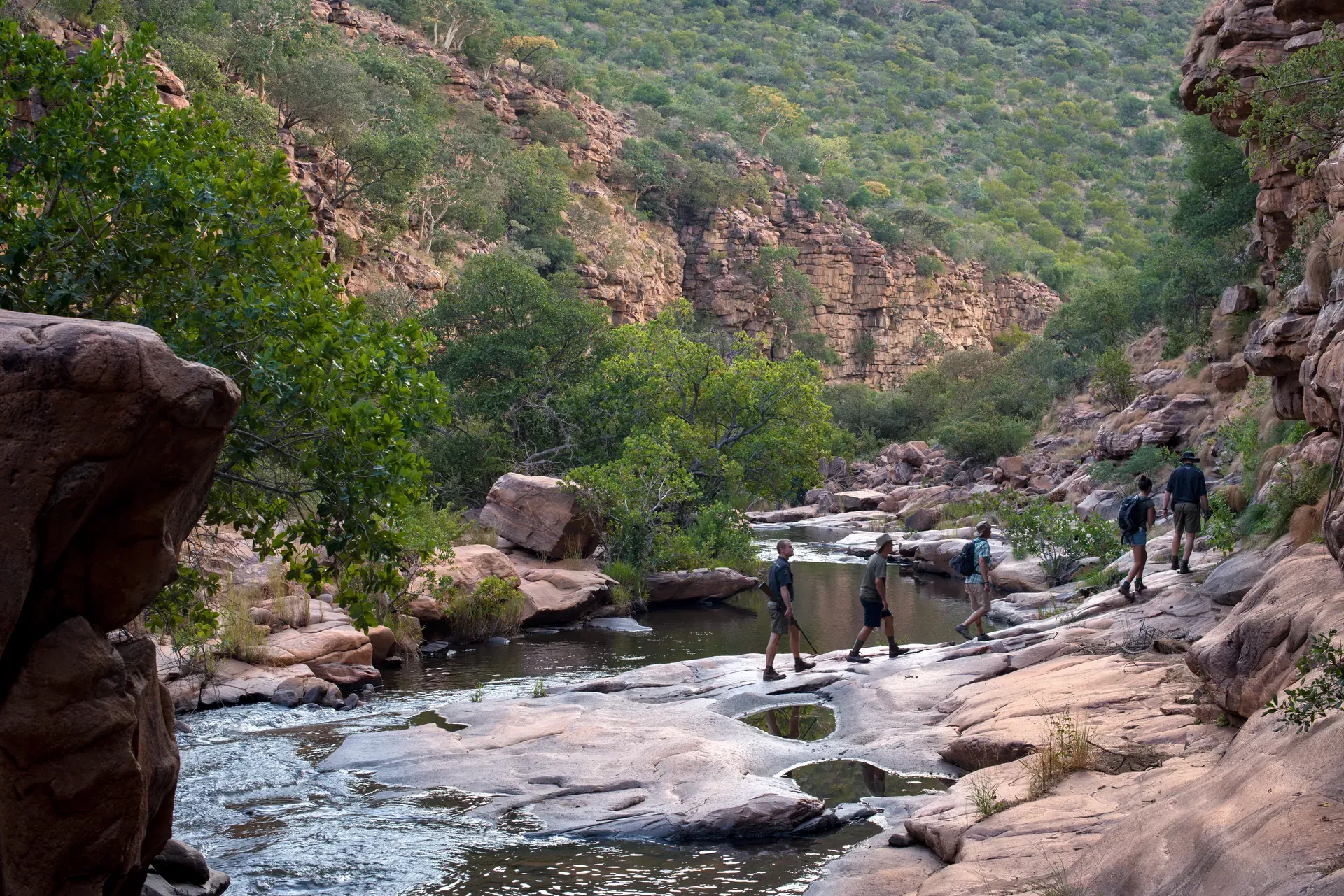 Rocky river and pools nestled among hills and vegetation on a bush walk trail
