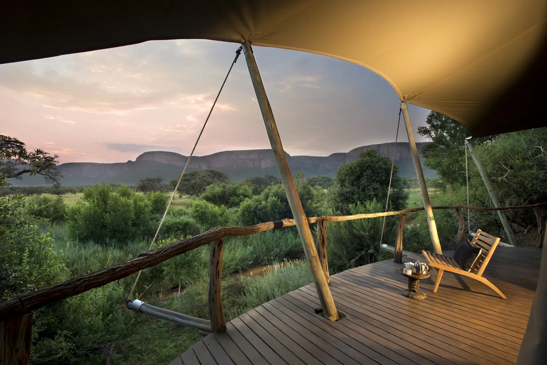 Private deck of a tented suite at Marataba Safari Lodge with sun umbrella, seating and scenic views of the bush and mountains