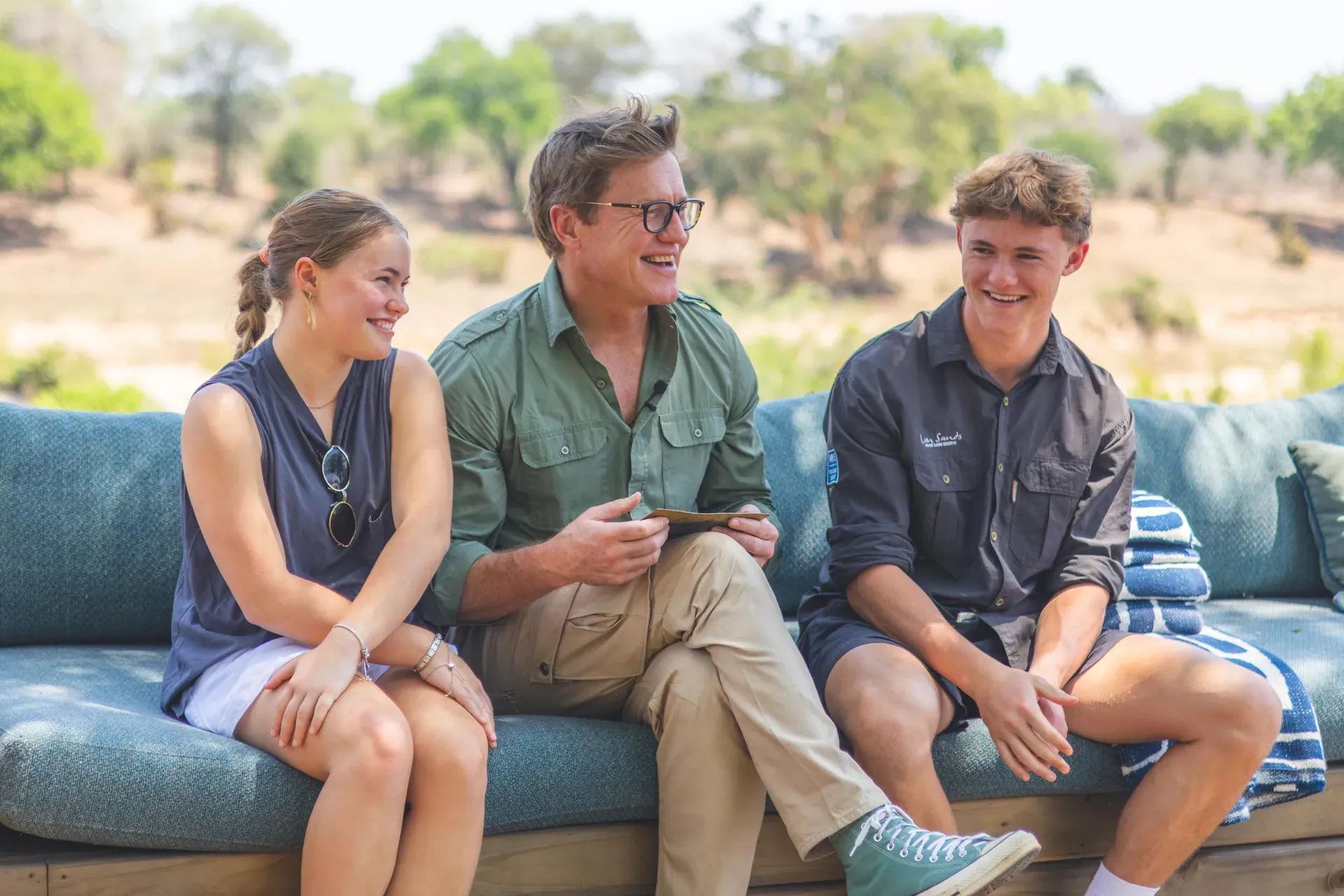 Group of young adults sitting together outdoors, laughing and chatting as part of the MORE family portrait