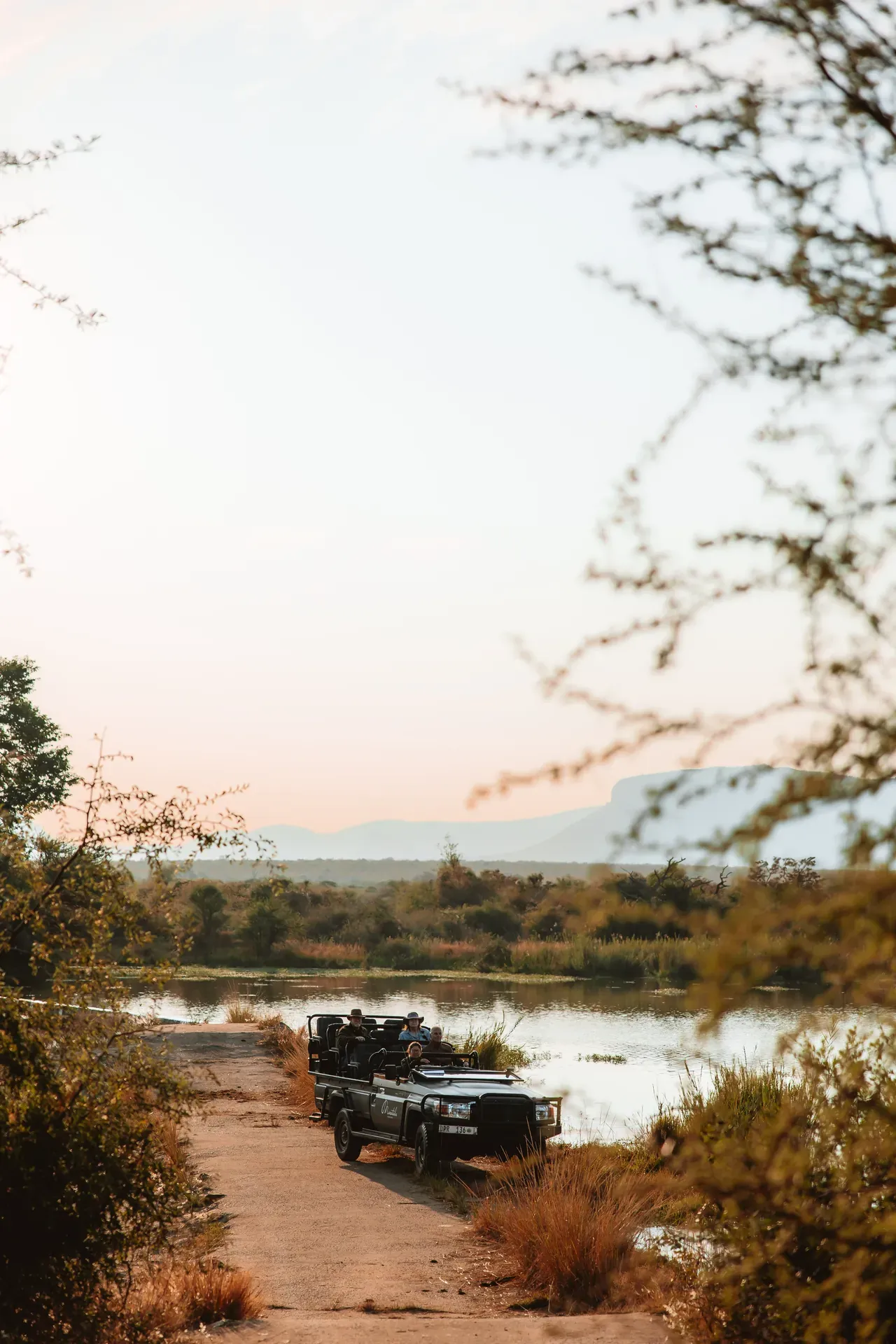 Guests on a game drive vehicle next to a river at Marataba.