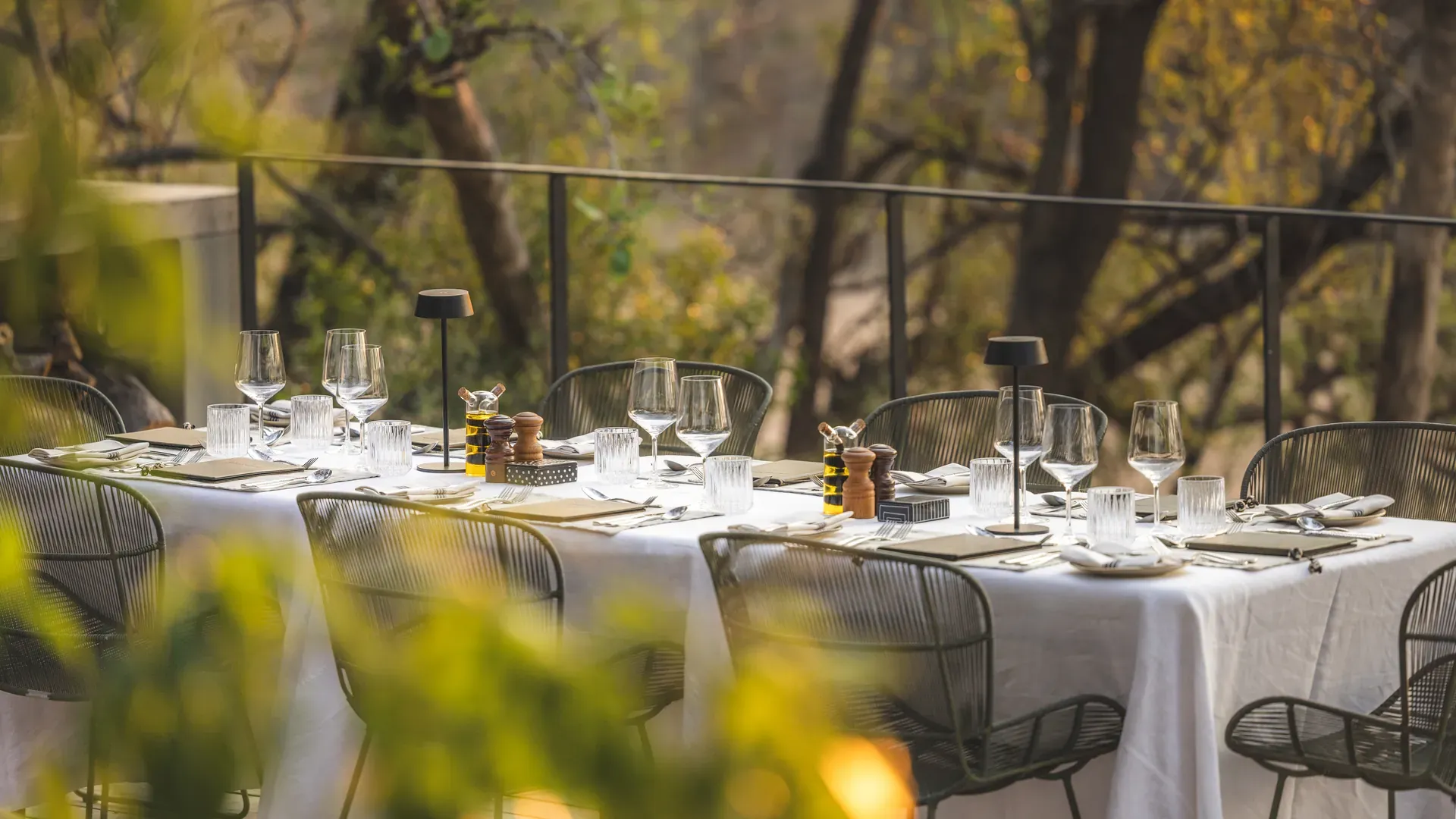 Elegant dining table set on a wooden deck in the African bush at Monwana Lodge