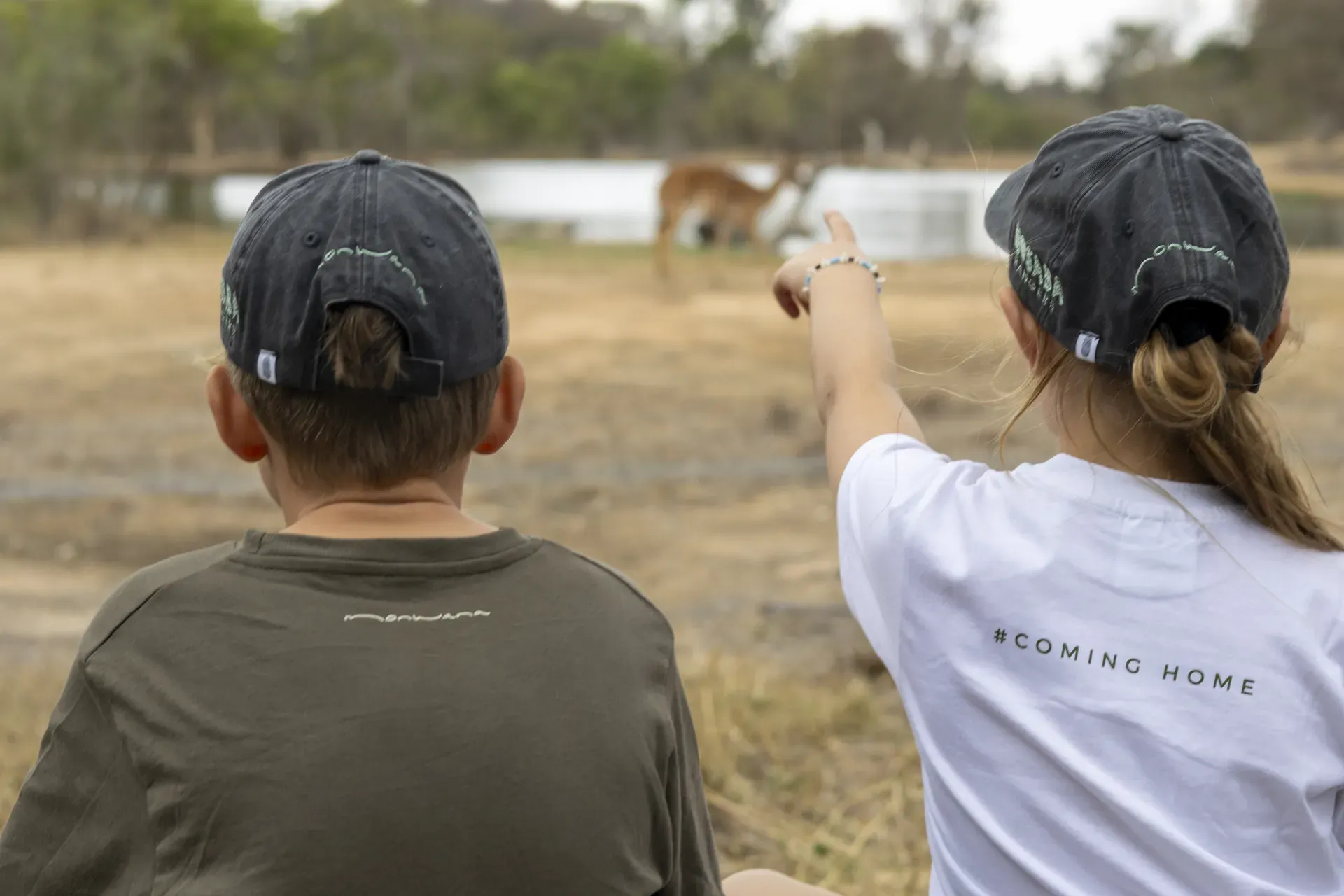 Children sitting at a watering hole observing wildlife during the Young Rangers program at Monwana.