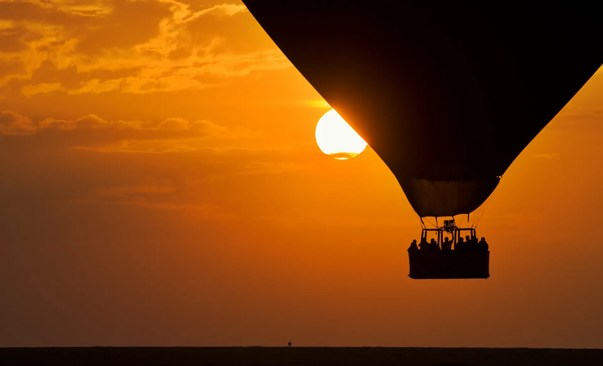 Hot air balloon silhouetted against an African sunset with guests aboard at Monwana Lodge.