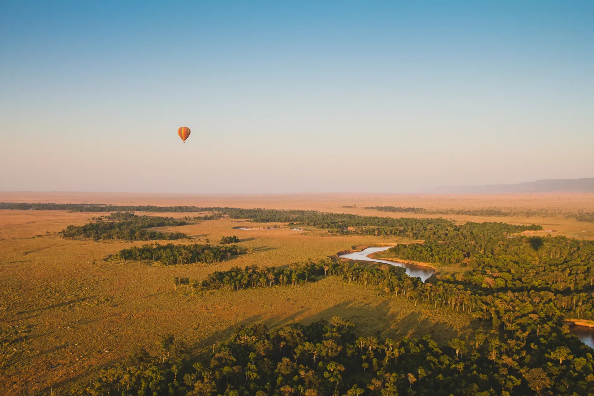Hot air balloon floating above the African wilderness near Monwana Lodge, with a river below, creating a serene and peaceful scene.