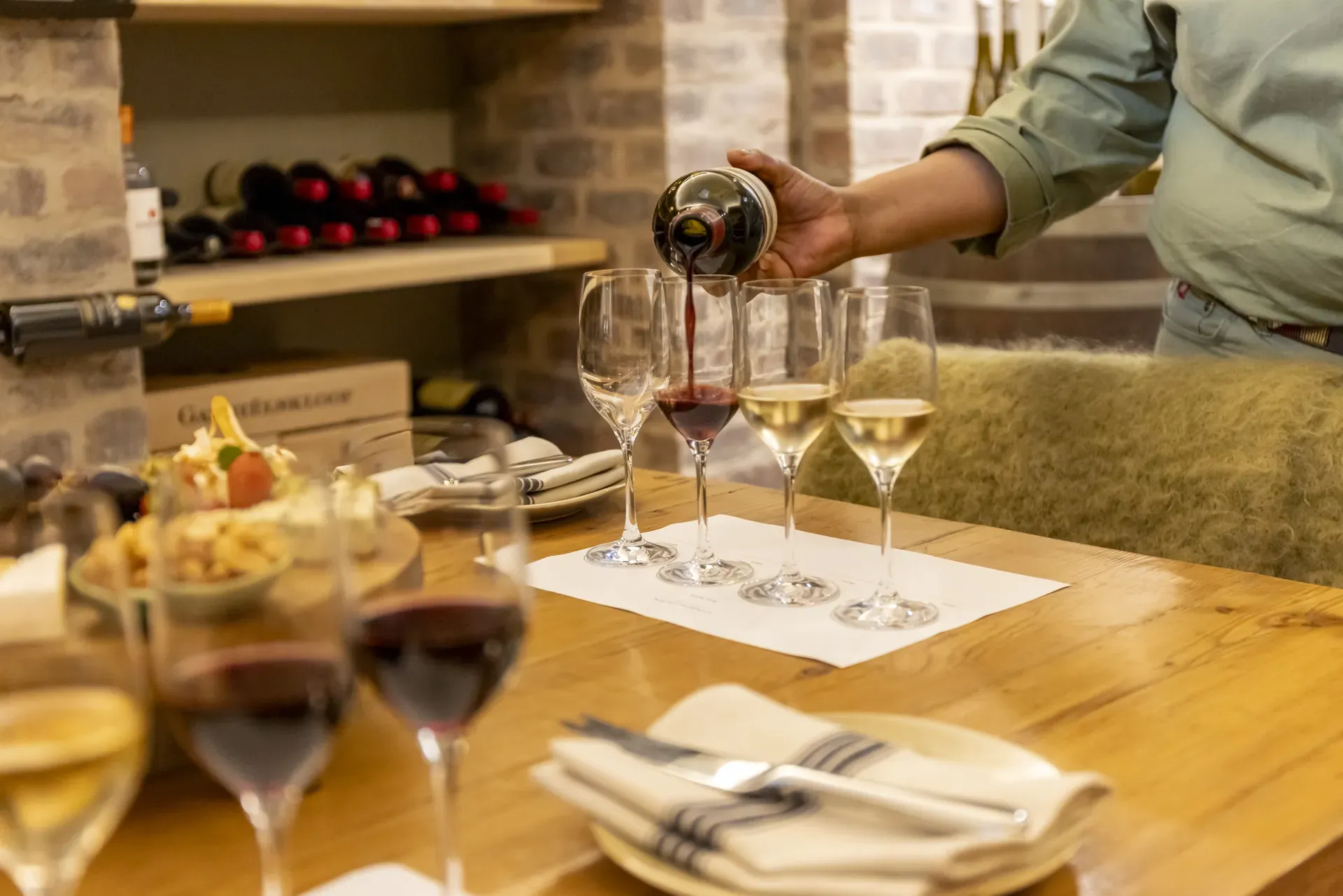 Wine being poured into glasses in the Monwana Lodge cellar, highlighting expert knowledge and service.