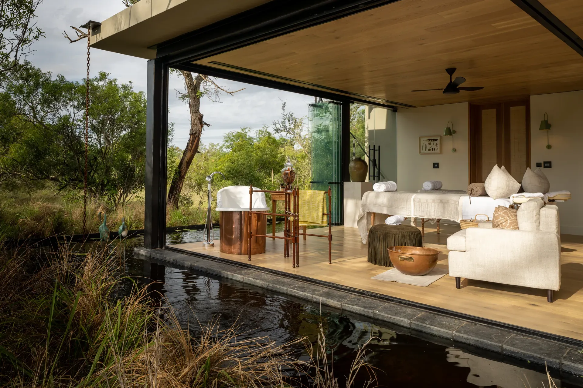 Tranquil spa setting at Monwana with a massage table beside a pond.