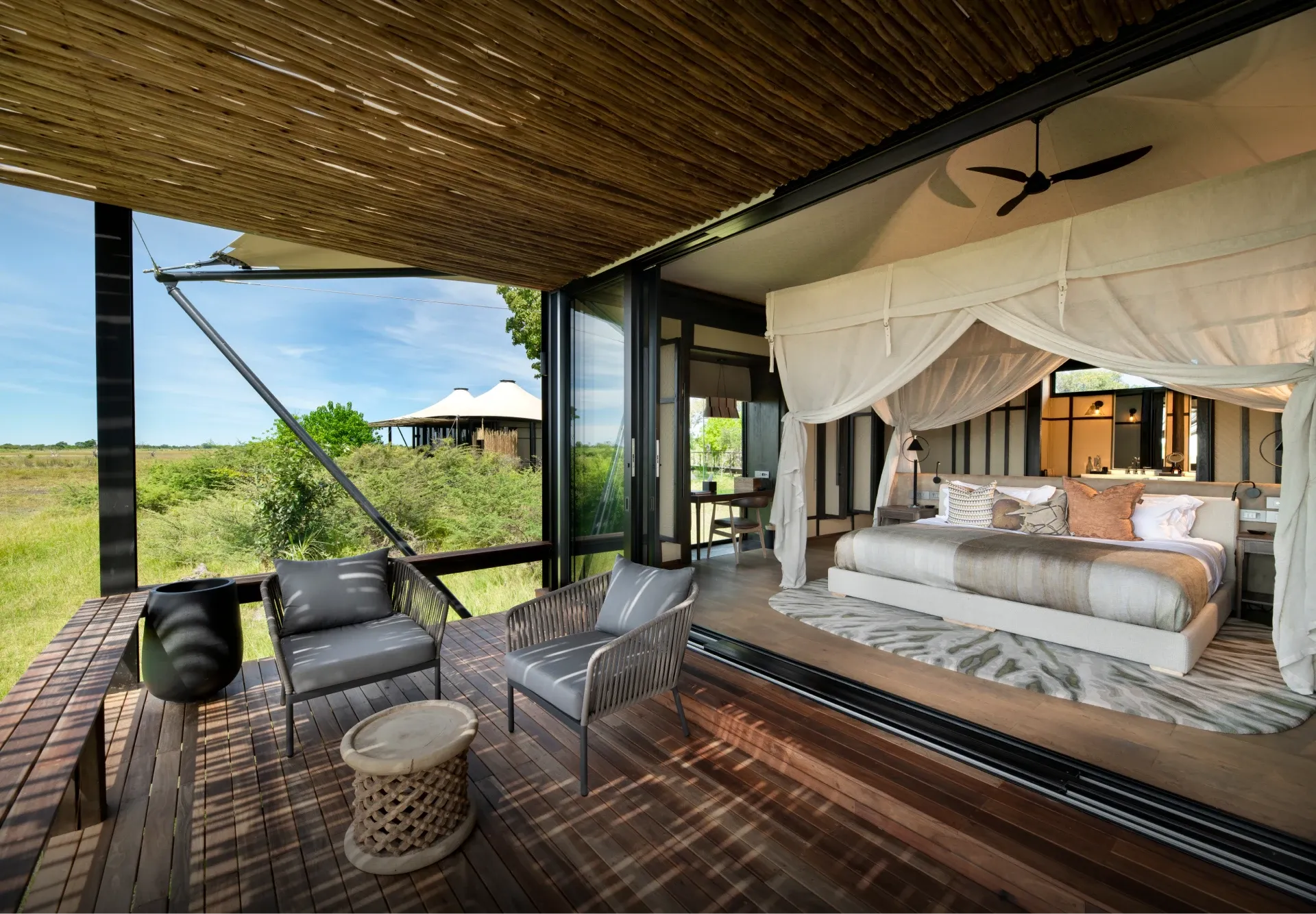 Luxury tented suite at Daunara Safari Camp with a king bed facing peaceful Okavango Delta waters.