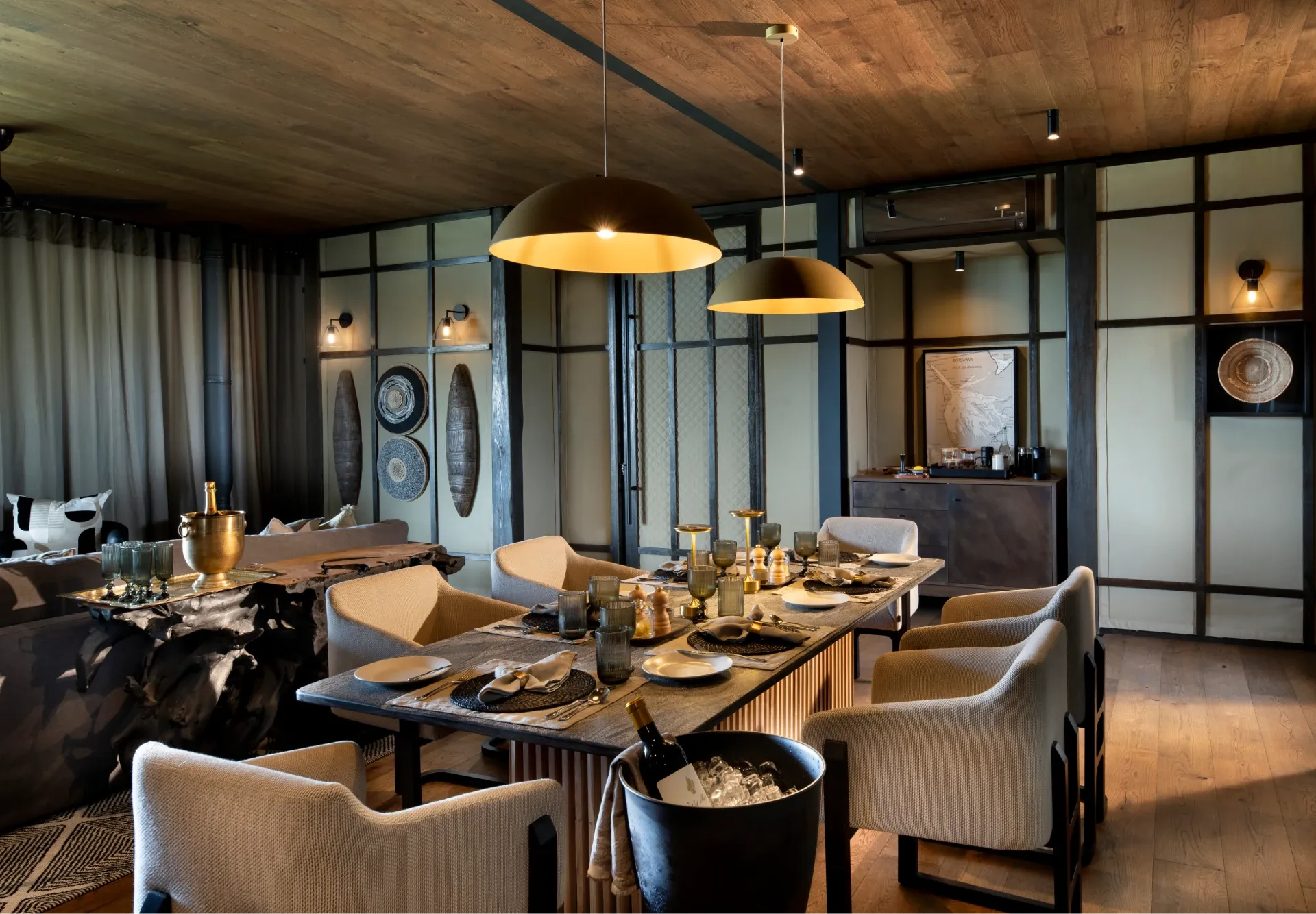 Candlelit dining table at Daunara Safari Camp, set with elegant place settings in warm, dim lighting overlooking the Okavango Delta ambiance.