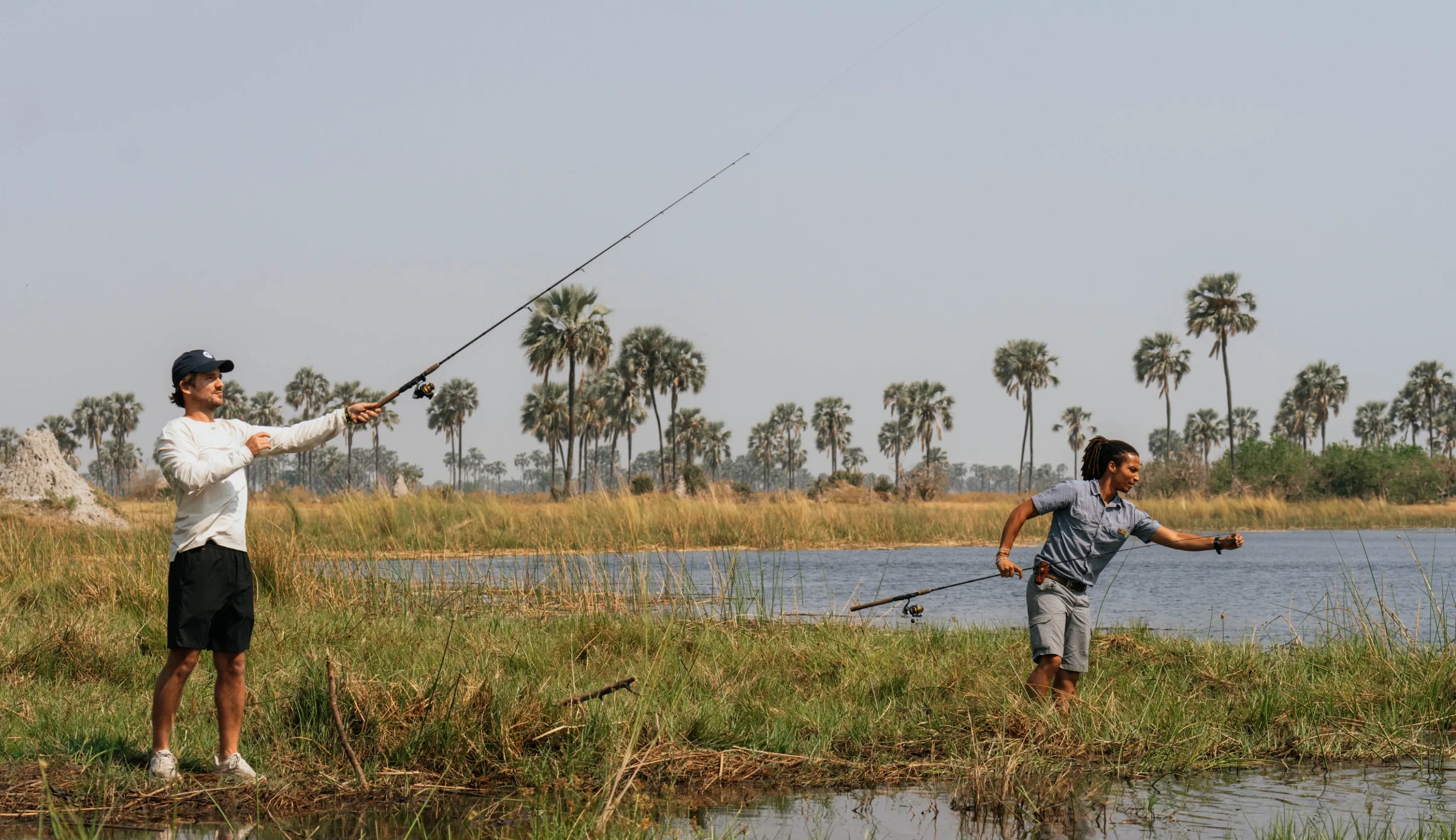 Guest and safari guide fishing in the Okavango Delta near Daunara Safari Camp, practicing catch-and-release.