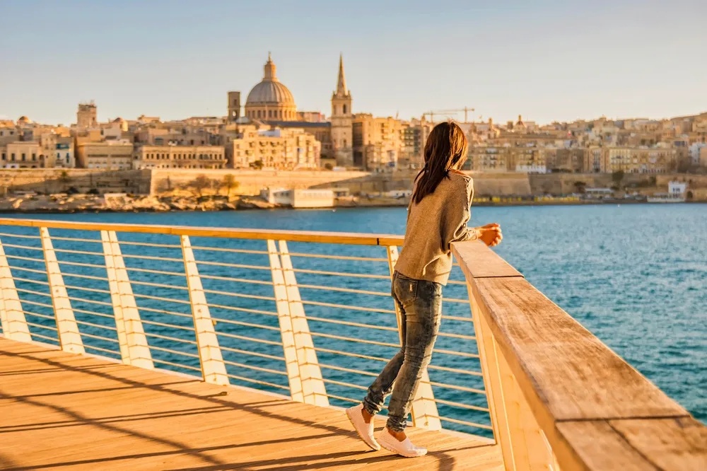 Woman looking at Valletta skyline from seafront promenade in Malta