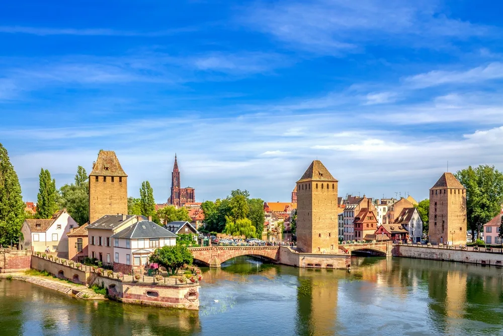 Scenic summer view of Strasbourg, France, featuring medieval towers, charming half-timbered houses, and tranquil canals—an idyllic destination for a last minute European summer holiday.
