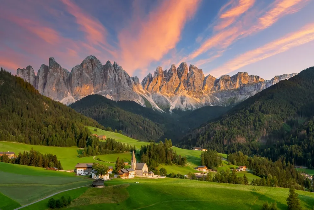 Stunning summer landscape of the Dolomites in northern Italy, with jagged mountain peaks, lush green valleys, and charming alpine villages—an ideal retreat for a peaceful summer holiday in nature.