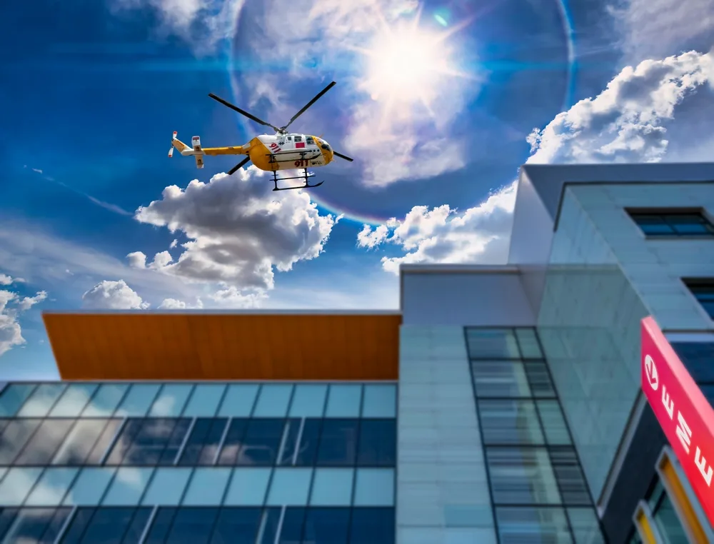 Air ambulance helicopter flying above hospital building during emergency medical response.