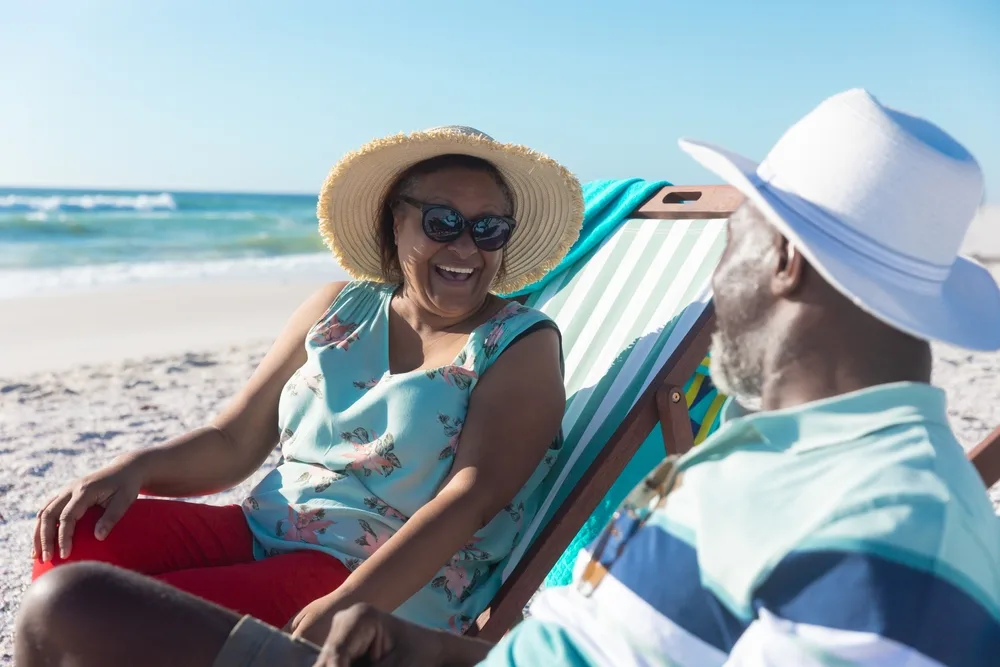 Older couple relaxing on a beach holiday, smiling and enjoying time together by the sea