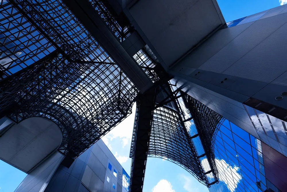 Kyoto Station’s modern steel and glass architecture with geometric roof structure and blue sky above