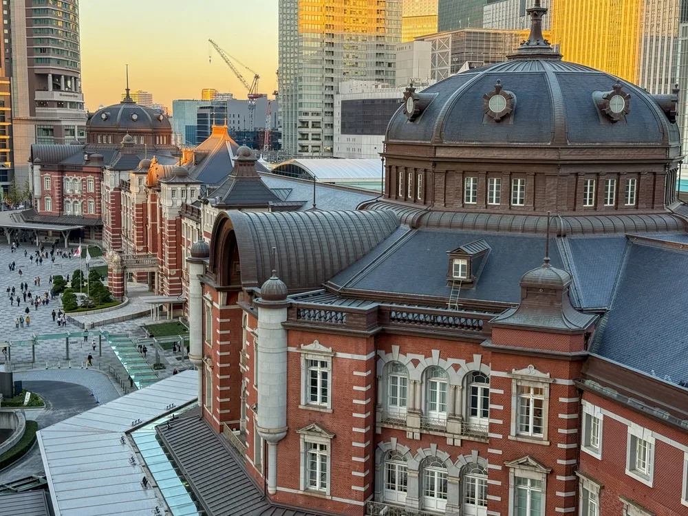 Tokyo Station Marunouchi building with historic red-brick facade, domed roof and surrounding skyscrapers in central Tokyo