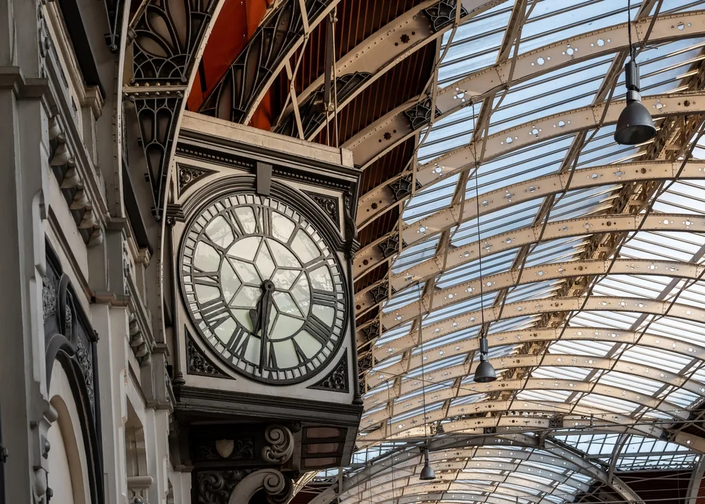 Paddington Station interior featuring iconic hanging clock, ornate ironwork and glass roof structure in London