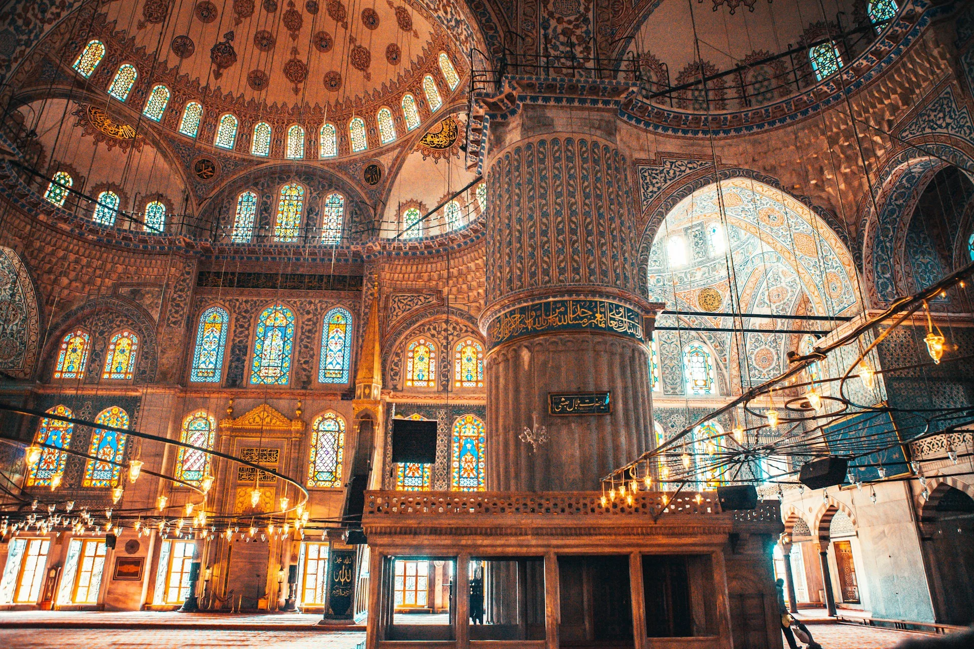 Blue Mosque interior in Istanbul, Turkey, featuring intricate blue tiles, stained-glass windows, domed ceilings and Islamic calligraphy.
