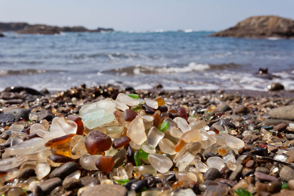 Picture shows the rounded glass of Glass Beach California, glinting in the sun.