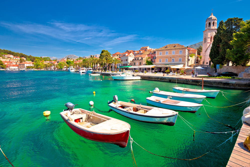 Picture shows a row of 5 boats bobbing in the clear waters of Croatia's Dalmatian coast.