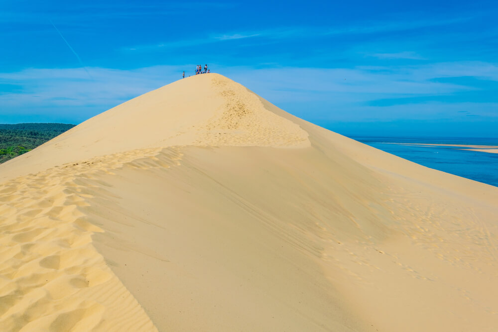 The Great Dune of Pyla in France is Europe's largest sand dune! The bright white sand soars into the blue sky.