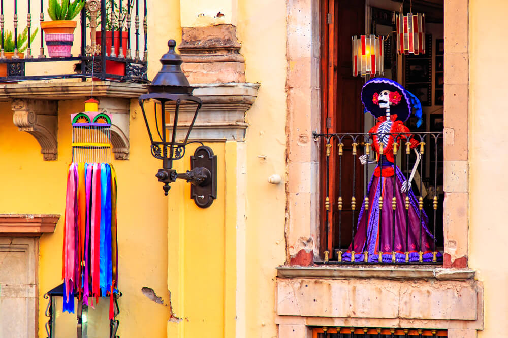 Day of the death. Traditional Mexican Catrina at the window of the old historic building, Mexico. An elegantly-dressed skeleton figure used as a symbol of the Day of the Dead